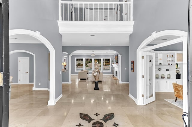 entrance foyer featuring ceiling fan, a high ceiling, arched walkways, and baseboards