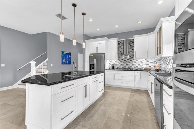 kitchen featuring stainless steel fridge, decorative backsplash, dark countertops, wall chimney range hood, and a sink