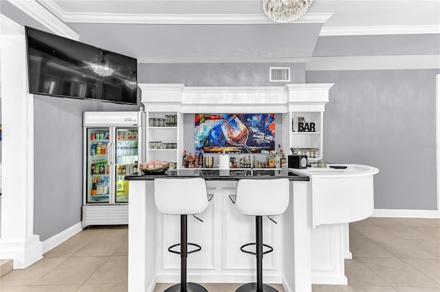 bar featuring light tile patterned floors, baseboards, visible vents, wet bar, and crown molding