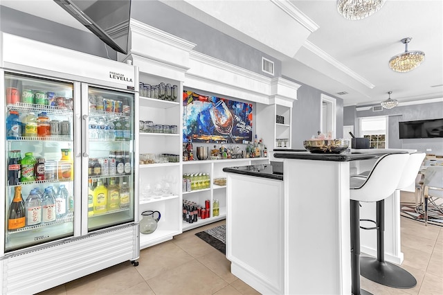 kitchen featuring dark countertops, stainless steel built in fridge, crown molding, a kitchen bar, and light tile patterned flooring