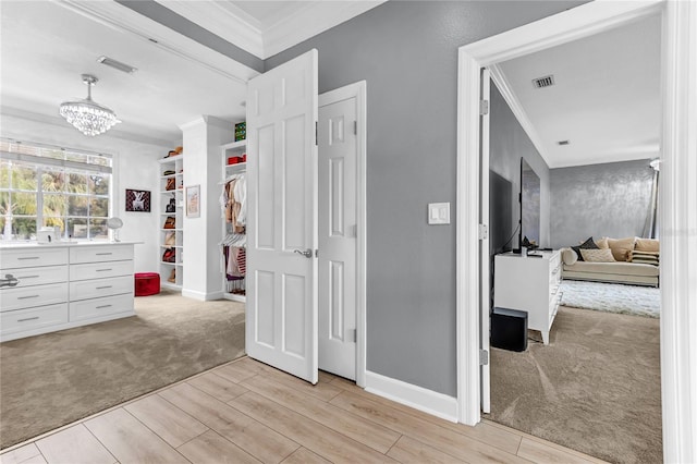 hallway with light wood-style flooring, light colored carpet, visible vents, and crown molding