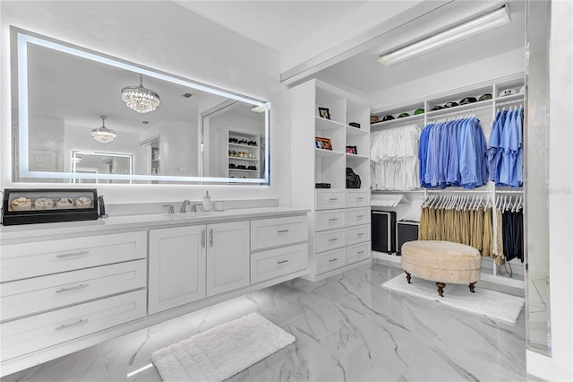 interior space featuring a chandelier, marble finish floor, vanity, and a spacious closet