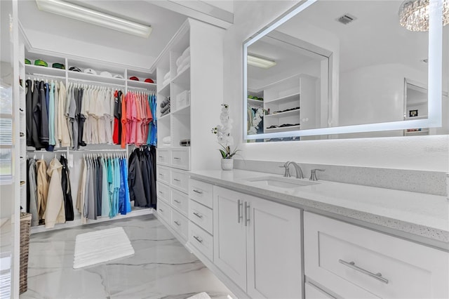 bathroom featuring marble finish floor, a spacious closet, visible vents, and vanity