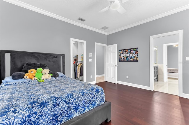 bedroom featuring baseboards, visible vents, ornamental molding, wood finished floors, and a spacious closet