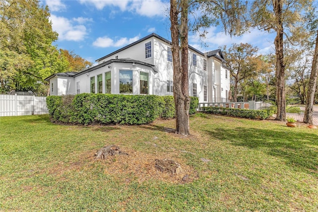 view of home's exterior featuring stucco siding, fence, and a yard