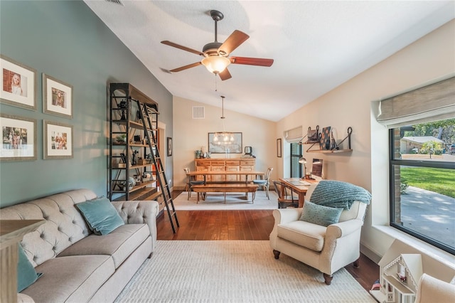 living room with dark wood-style floors, visible vents, vaulted ceiling, baseboards, and ceiling fan with notable chandelier