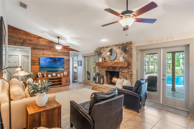 living area featuring french doors, visible vents, light tile patterned flooring, vaulted ceiling, and wood walls