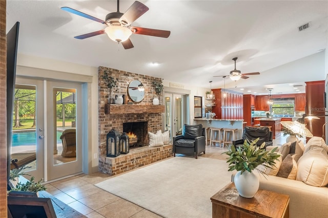 living room with light tile patterned floors, visible vents, ceiling fan, french doors, and a brick fireplace