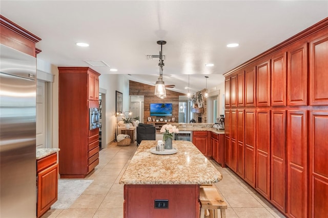 kitchen featuring light tile patterned floors, lofted ceiling, open floor plan, a center island, and stainless steel built in fridge