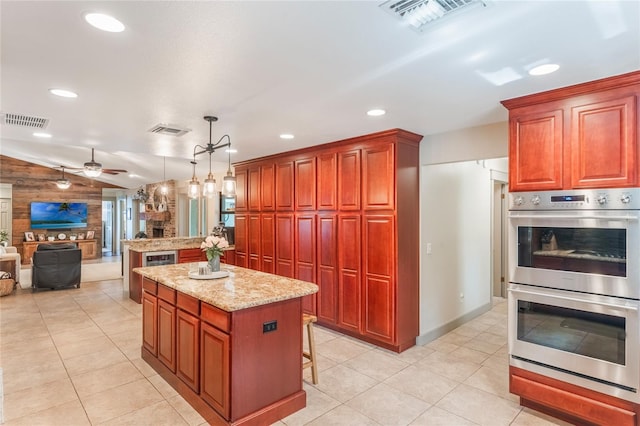 kitchen featuring a kitchen island, visible vents, open floor plan, and stainless steel double oven