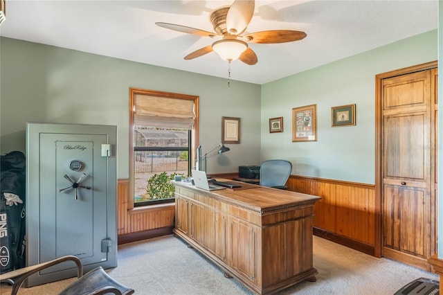 office featuring a wainscoted wall, a ceiling fan, wood walls, and light colored carpet