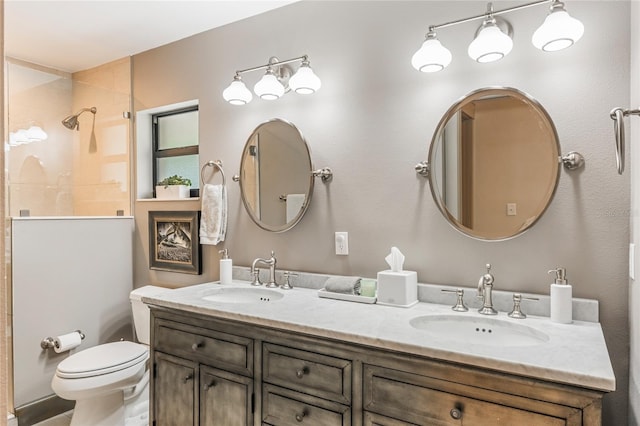 bathroom featuring toilet, double vanity, a tile shower, and a sink