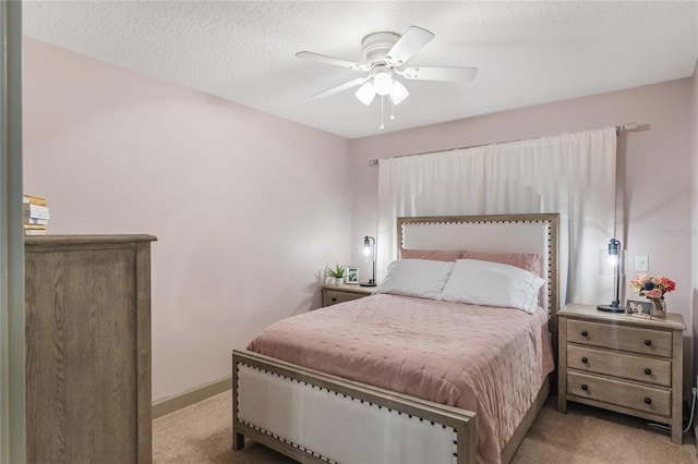 carpeted bedroom featuring ceiling fan, a textured ceiling, and baseboards