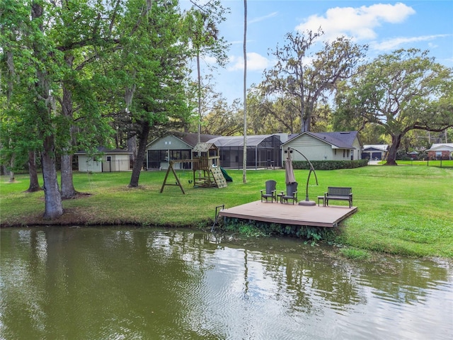 view of dock with a deck with water view, playground community, and a lawn