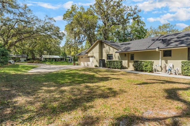 view of side of property featuring a garage, a yard, driveway, and stucco siding