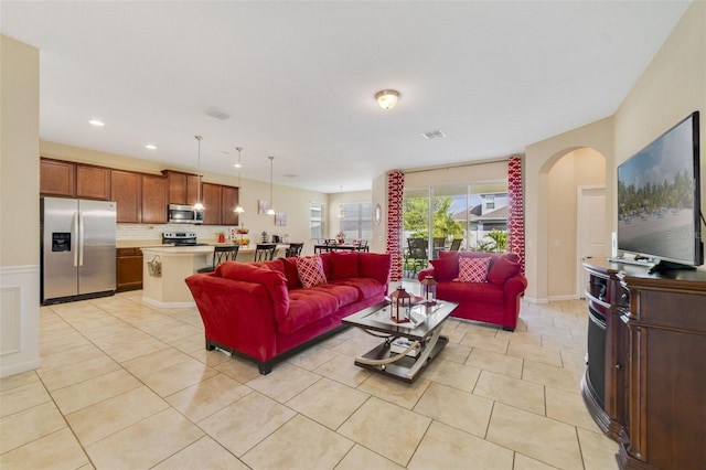 living area with arched walkways, visible vents, recessed lighting, and light tile patterned floors