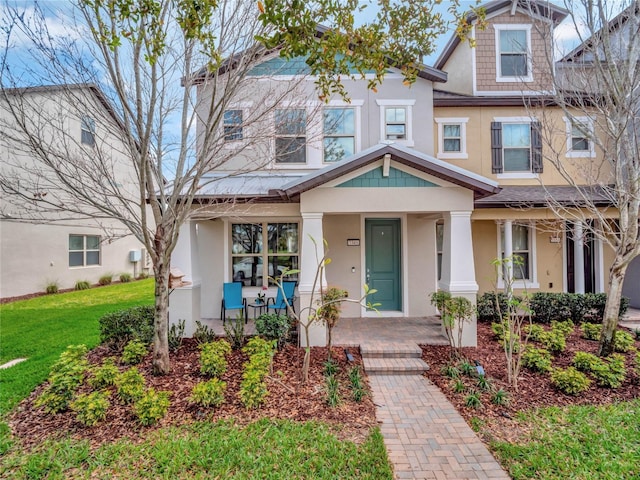 view of front of property with a porch, a front lawn, and stucco siding