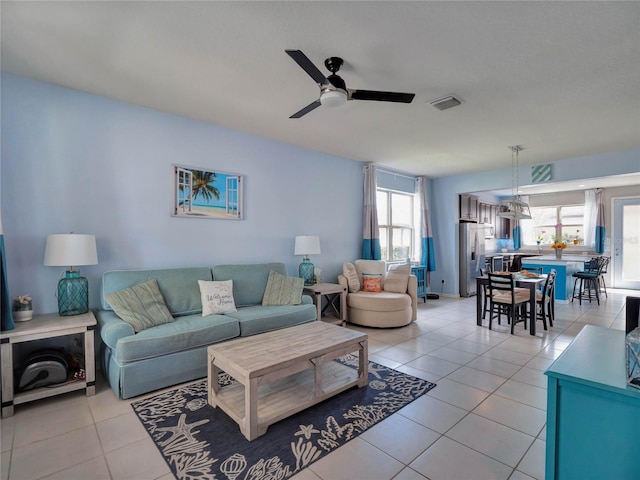 living area with visible vents, ceiling fan, and light tile patterned floors