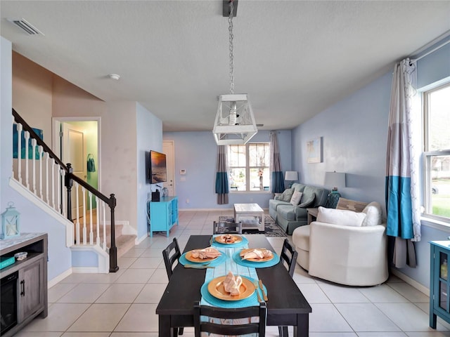 dining area with light tile patterned floors, stairway, visible vents, and baseboards