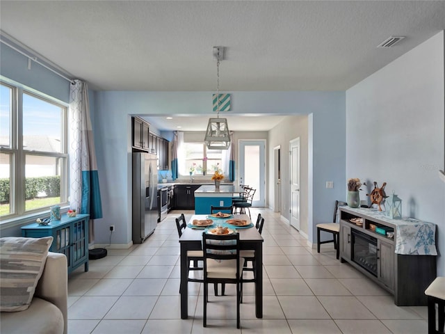 dining room with visible vents, a textured ceiling, baseboards, and light tile patterned floors