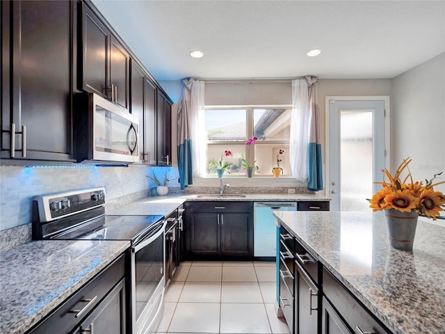 kitchen featuring light tile patterned floors, light stone countertops, stainless steel appliances, a sink, and recessed lighting