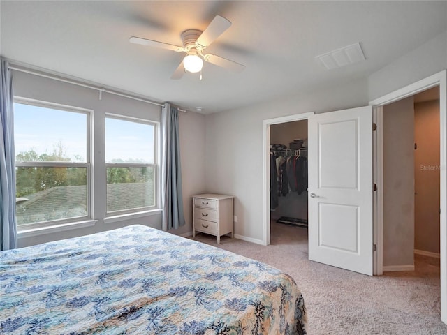 bedroom featuring light carpet, baseboards, visible vents, ceiling fan, and a spacious closet