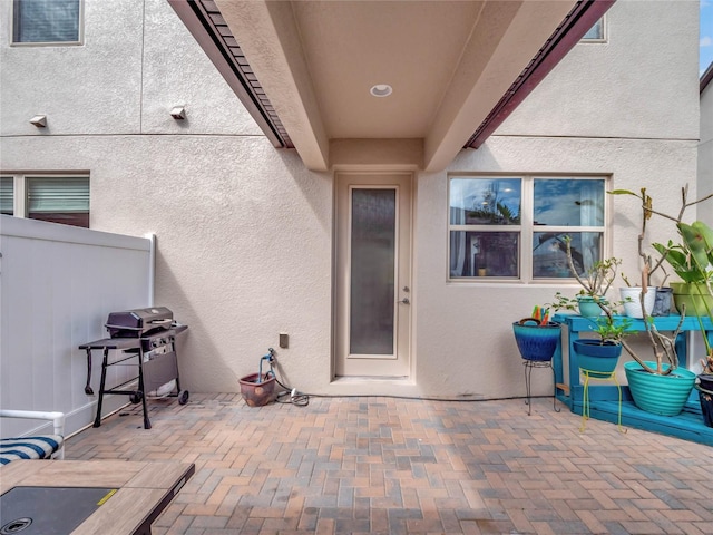 doorway to property featuring a patio area, fence, and stucco siding