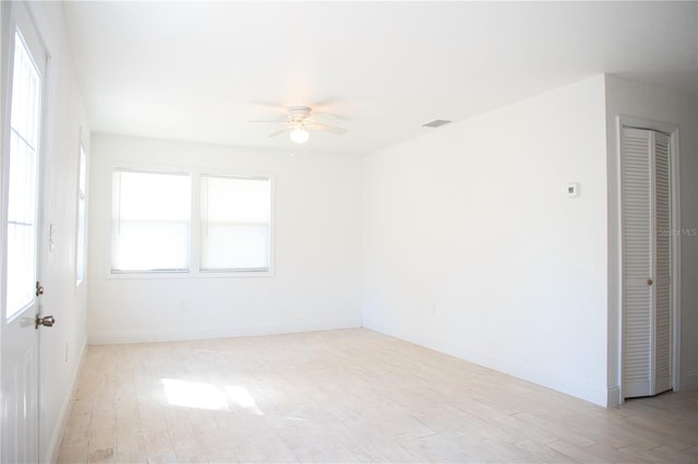 spare room featuring baseboards, ceiling fan, and light wood-style floors