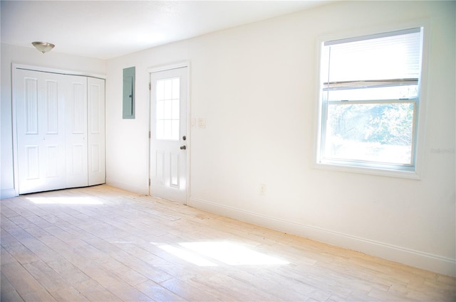 unfurnished room featuring electric panel, plenty of natural light, baseboards, and wood finished floors