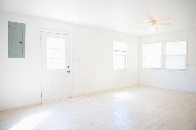 unfurnished room with ceiling fan, light wood finished floors, electric panel, and baseboards