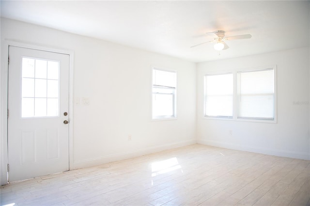 spare room with a ceiling fan, light wood-type flooring, and baseboards