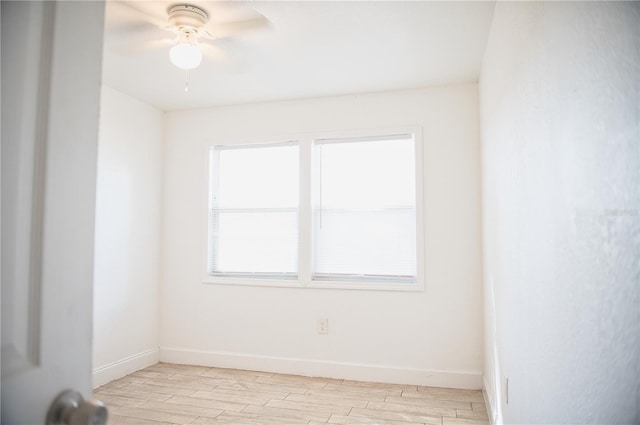 spare room featuring light wood-type flooring, ceiling fan, and baseboards