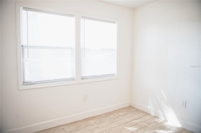 spare room featuring light wood finished floors and baseboards