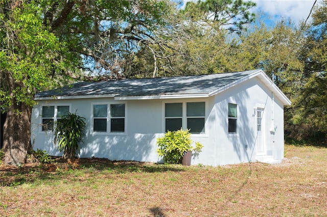 view of side of home with a lawn and stucco siding