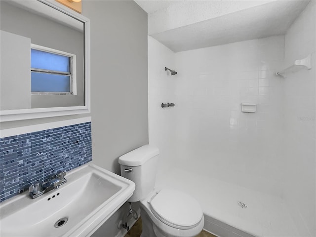 bathroom with tasteful backsplash, a shower, a sink, and toilet