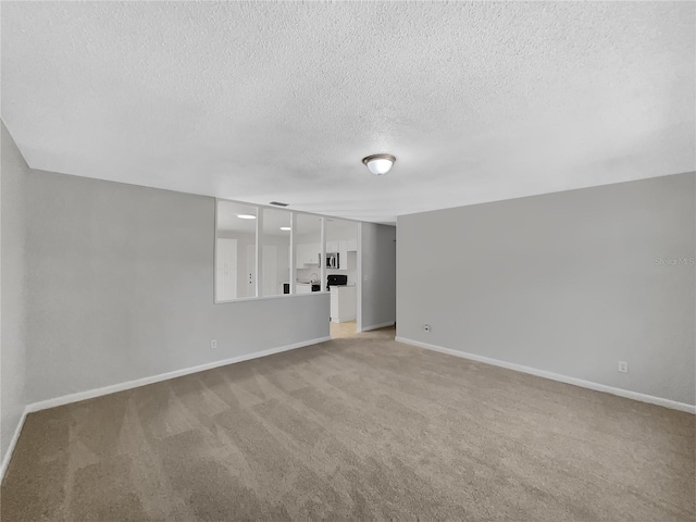 unfurnished living room with light carpet, a textured ceiling, and baseboards