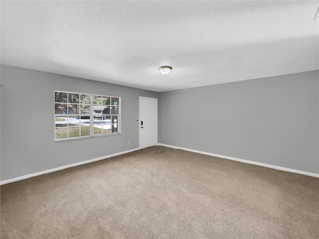 spare room featuring carpet flooring, a textured ceiling, and baseboards