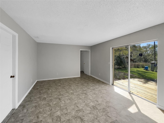 empty room with baseboards, visible vents, a textured ceiling, and tile patterned floors