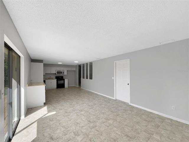 unfurnished living room featuring a textured ceiling and baseboards