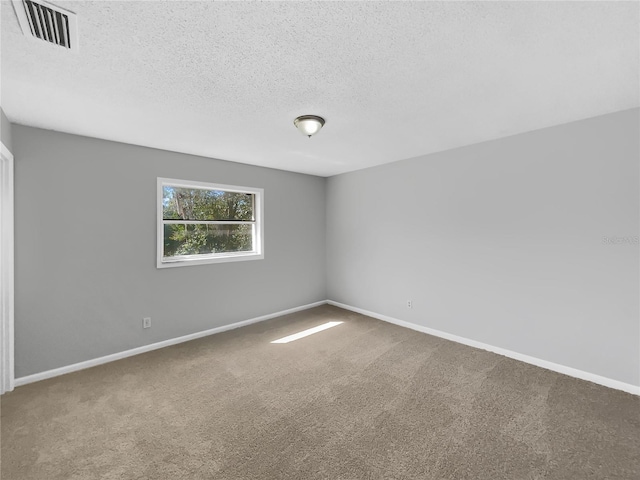 carpeted empty room featuring visible vents, a textured ceiling, and baseboards