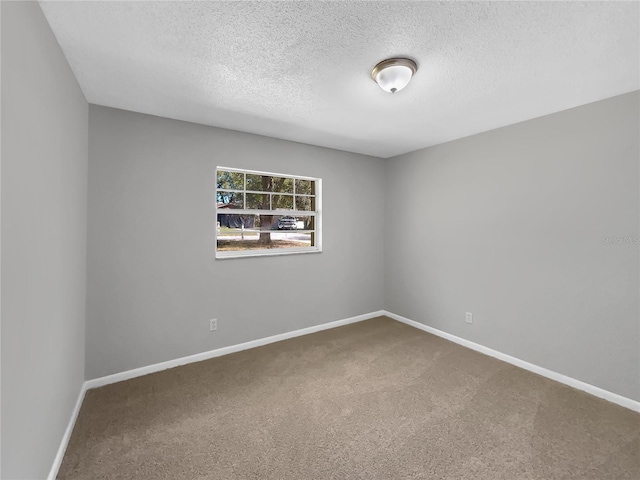 unfurnished room with carpet floors, a textured ceiling, and baseboards