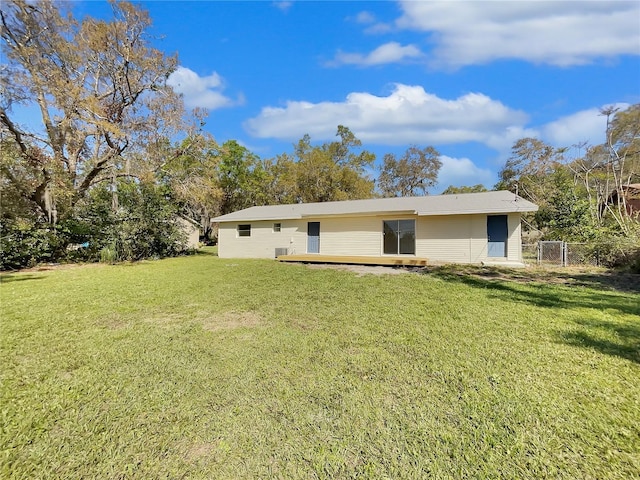 rear view of property with fence, a deck, and a yard