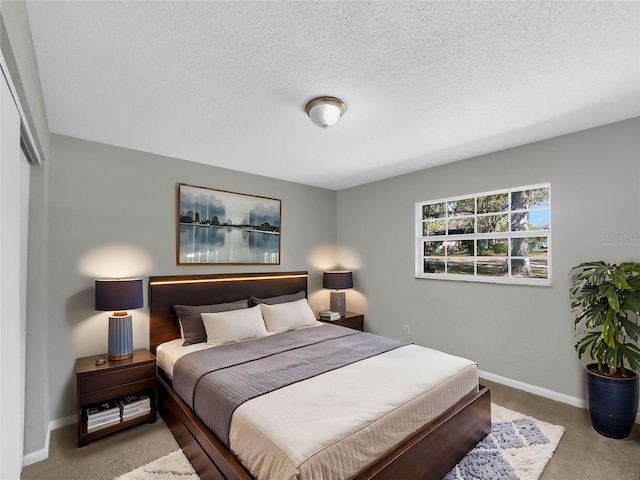 bedroom with baseboards, a textured ceiling, and carpet flooring