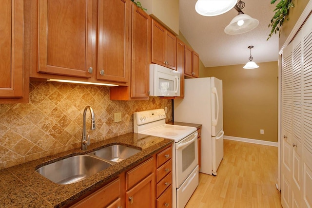 kitchen with white appliances, brown cabinets, a sink, light wood-type flooring, and backsplash