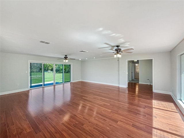 empty room featuring visible vents, ceiling fan, baseboards, and wood finished floors