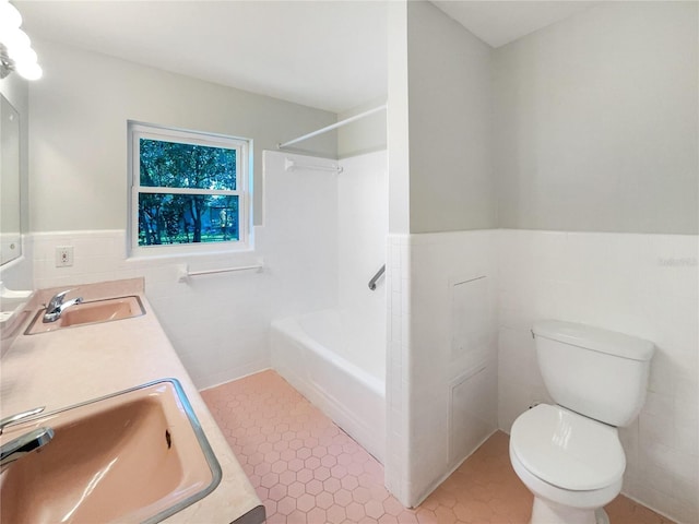 full bath with wainscoting, a sink, and tile walls