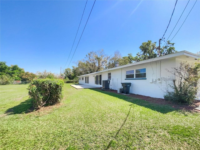 rear view of house featuring central AC unit and a lawn