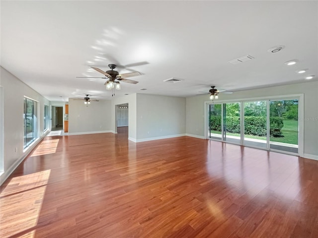 unfurnished living room featuring baseboards, visible vents, and wood finished floors