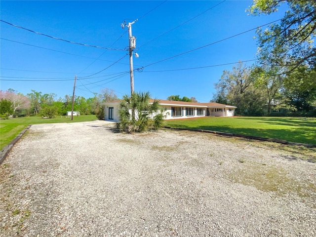 view of front of home with a front lawn and gravel driveway