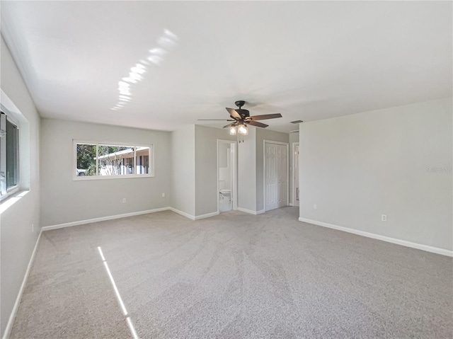 empty room with baseboards, a ceiling fan, and light colored carpet